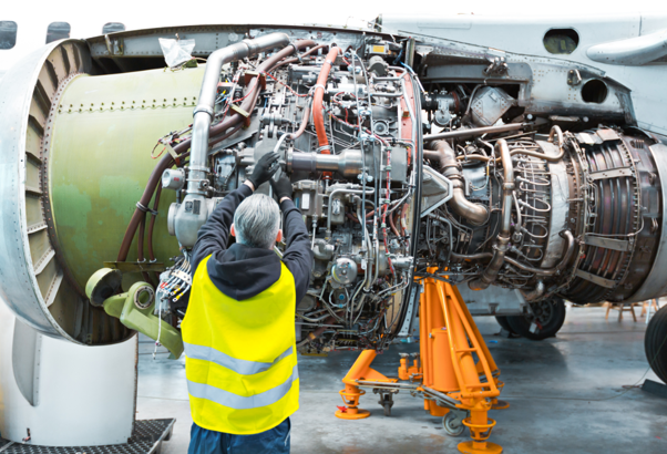 Engineer using an aerospace parts washer to clean and maintain an aircraft engine during aerospace manufacturing.